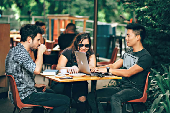 a group of people sitting at a table with a laptop