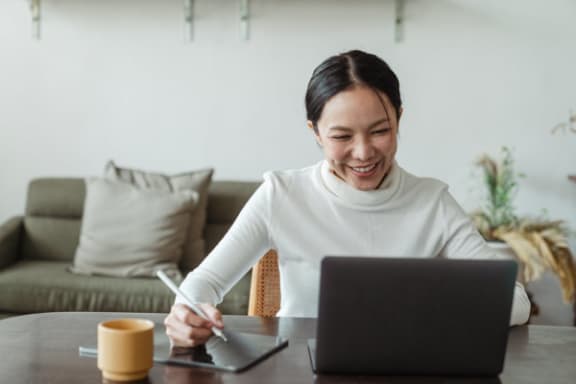 a woman laughing while working on a laptop computer