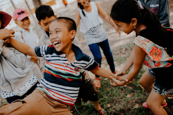 a group of children holding hands while playing in the grass