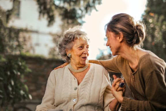 an older woman sitting on a bench talking to another woman