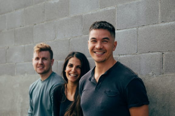 three people standing in front of a brick wall