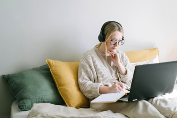 a woman sitting on a bed using a laptop computer