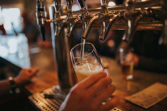 A person is pouring a beer from a tap into a glass.