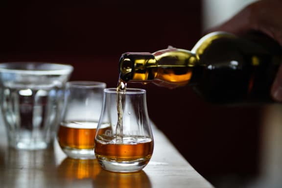 a bottle of whiskey being poured into a glass on a table