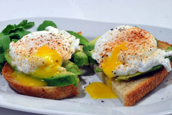 a white plate topped with eggs and avocado on toast