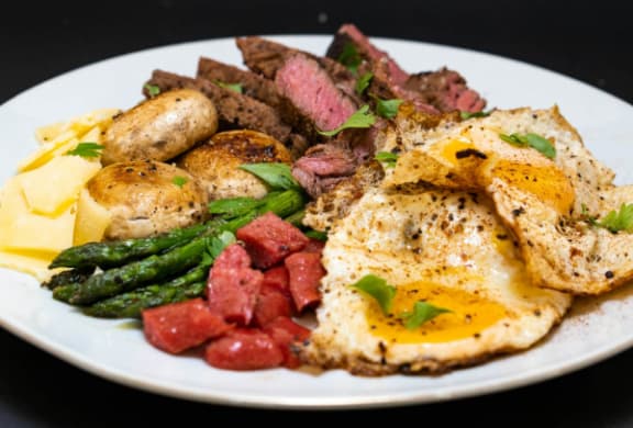 a plate of food with eggs meat and asparagus