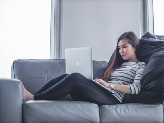 a woman sitting on a couch using a laptop computer