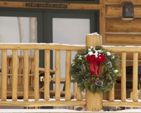 a christmas wreath on the railing of a porch