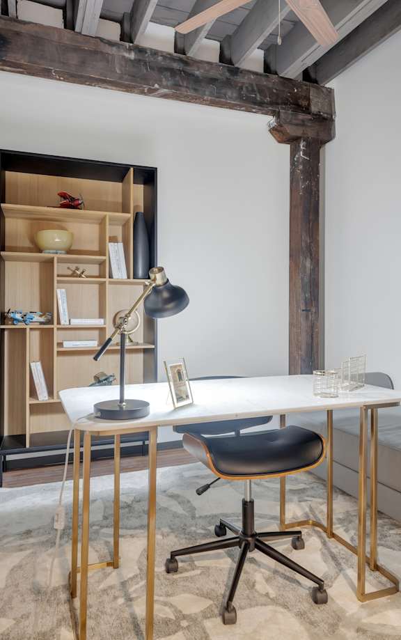 A room with a desk, chair, and a picture on the wall.