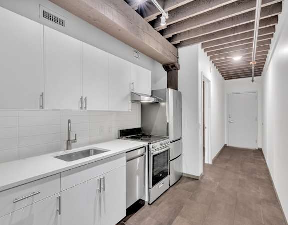 A kitchen with white cabinets and a wooden ceiling.