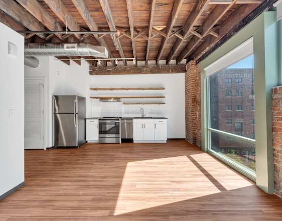 A kitchen with wooden floors and a brick wall.