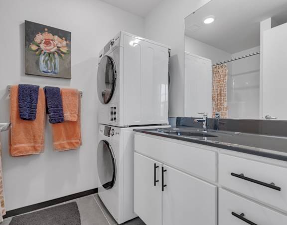 A laundry room with a washer and dryer, a sink, and a mirror.