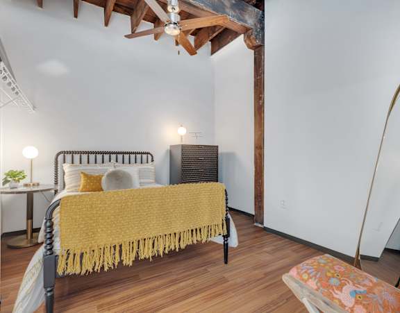 A bedroom with a bed covered in a yellow blanket.