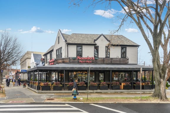 people walking down a sidewalk in front of a restaurant