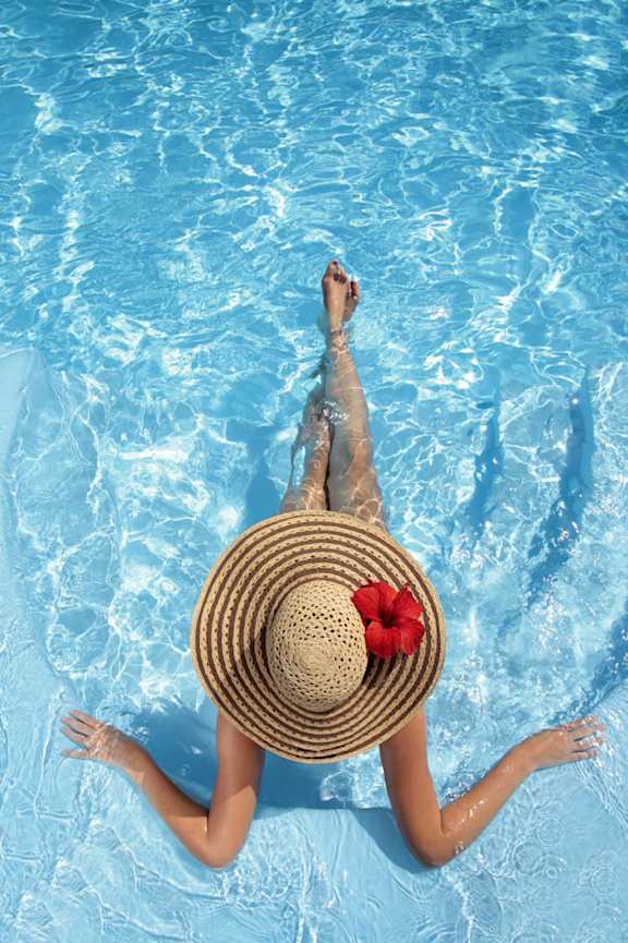 A woman in a straw hat floats in a pool.