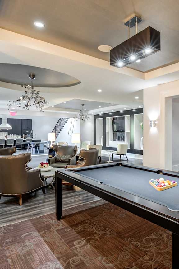 A billiard table is in the middle of a room with a chandelier hanging from the ceiling.