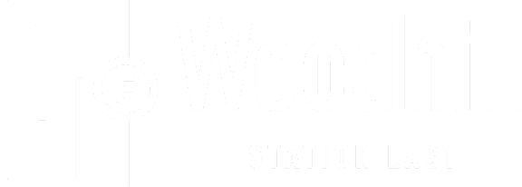 A black and white image of a sign for Woodhill Station East.