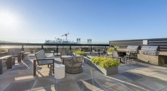 a roof terrace with tables and chairs and a view of the ocean