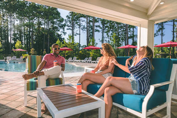 Four people are sitting on chairs by a pool.