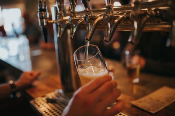 a person pouring beer into a glass in a bar