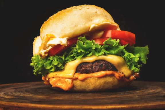 a cheeseburger with lettuce and tomato on a bun