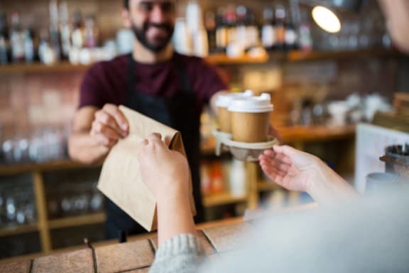 a man handing a cup of coffee to a customer at a bar