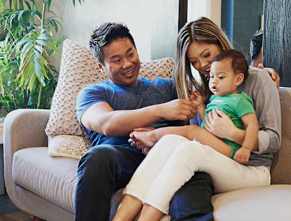 A man and woman sitting on a couch with a baby.