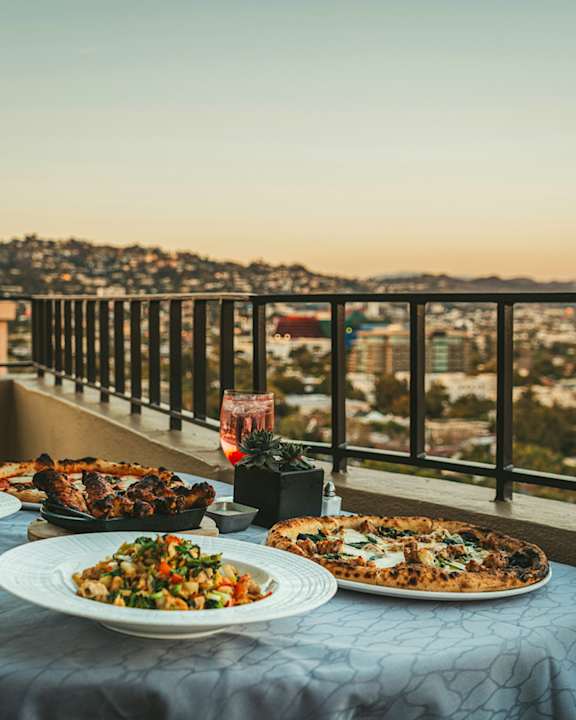 A table with two plates of food on it with a view of a city in the background.