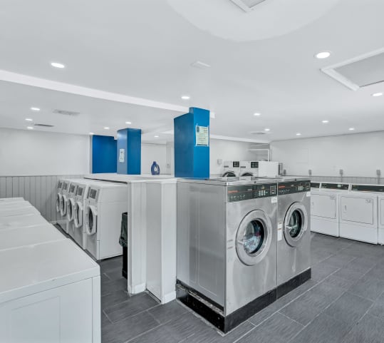 a large laundry room with washers and dryers and a row of washing machines