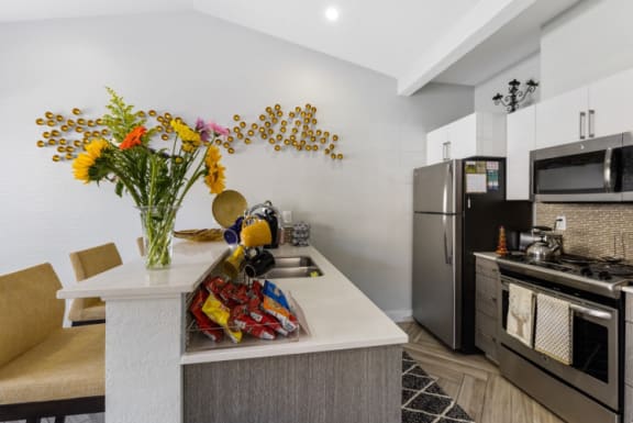 a kitchen with stainless steel appliances and a counter with flowers