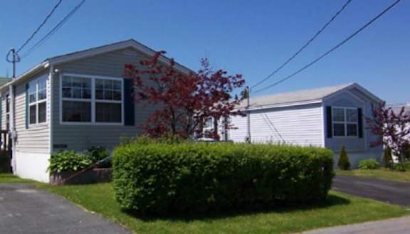 A house with a grey roof and a white house in the background.