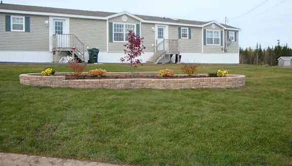 A grey house with a red tree in front.