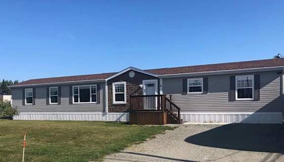 A mobile home with a brown roof and a white door.