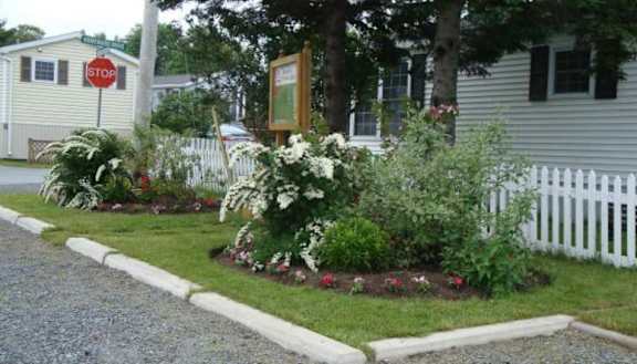 A white picket fence with a garden in front of a house.
