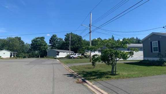 A residential street with houses on both sides and a clear blue sky.