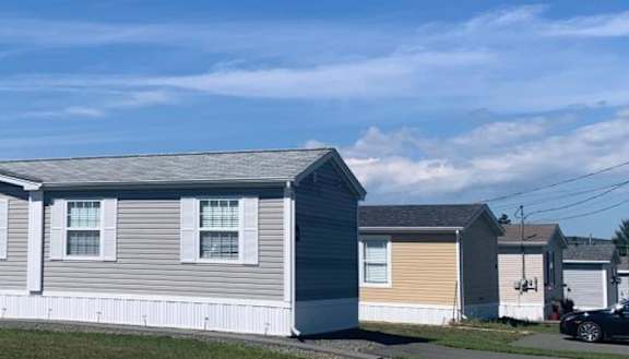 A row of mobile homes with a car parked in front of the first one.