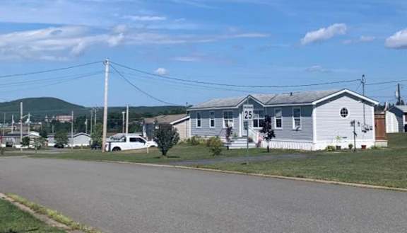 A white building with a sign that reads "25" sits in front of a grassy area.