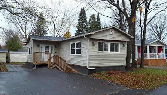 A house with a grey siding and a brown deck.