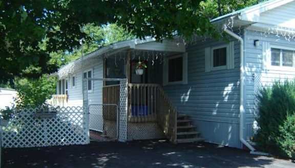 A house with a white picket fence and a tree in front.