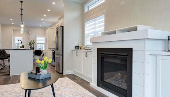 A modern living room with a fireplace and a dining area.