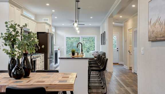 A modern kitchen with a wooden table and black chairs.