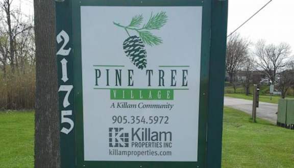 A sign for Pine Tree Village by Killam Properties Inc.