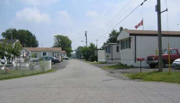 A street view with a house on the right and a car parked in front.