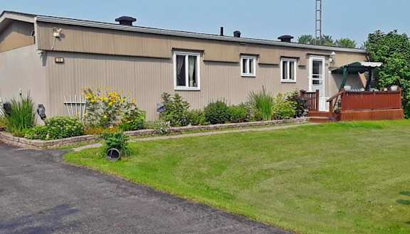 A house with a grey exterior and a green lawn in front.