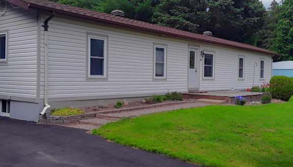 A house with a grey siding and a red roof.