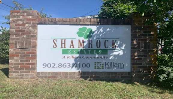 A sign for Shamrock Estate, a Killam Community, is displayed on a brick wall.