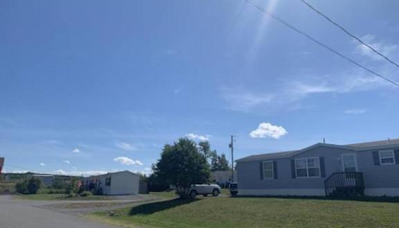 A sunny day in a residential area with houses and a car parked on the street.