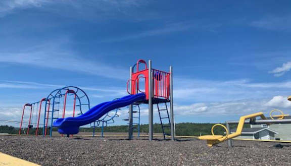 A playground with a blue slide and red and yellow structures.