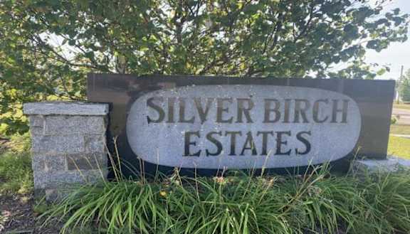 A sign that says Silver Birch Estates is surrounded by plants.