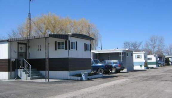A blue car is parked in front of a white and black building.